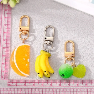 Detail view of resin fruit keychains with scale showing orange and banana slice sizes