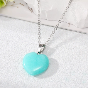 Detailed macro view of heart-shaped blue natural stone pendant on a silver box chain necklace