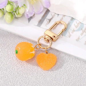 Detail of creative orange fruit keychain with sugar-like frosted texture and golden clasp