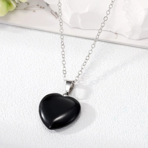 Detailed macro shot of a heart-shaped black stone pendant with polished silver chain