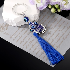 Vintage evil eye owl keychain with blue rhinestones and tassel on a decorative background