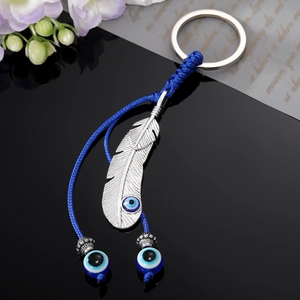 Porte-clés ethnique avec plume argentée, œil protecteur et pompons perlés bleus élégants