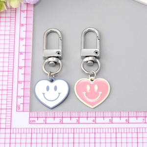 Porte-clés cœur émaillé avec visage souriant en bleu et rose avec fermoirs mousquetons argent