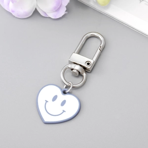 Gros plan d'un porte-clés en cœur avec smiley bleu et bordure violet clair