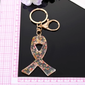 Floral resin bow keychain with dried flowers and gold metal ring on black background