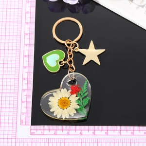 Porte-clés cœur transparent avec de vraies marguerites séchées et étoile dorée