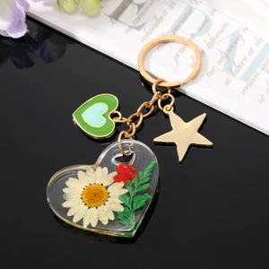 Détail d'un porte-clés en résine en forme de cœur avec marguerites et fleurs séchées