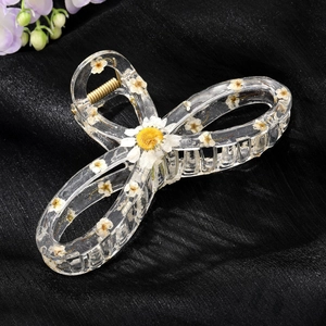 Transparent resin hair claw with dried white daisies in a stylish bow design