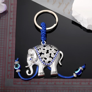 Vintage elephant keychain with rhinestone details and blue evil eye charms on black backdrop