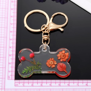 Handmade bone-shaped resin keychain with real dried flowers and golden metal clip