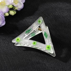 Detail view of triangular matte hair claw with green floral patterns and metal spring