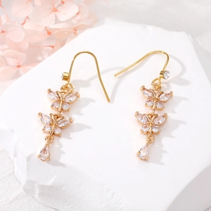 Detailed close-up of golden butterfly earrings with sparkling pear-cut zircon crystals