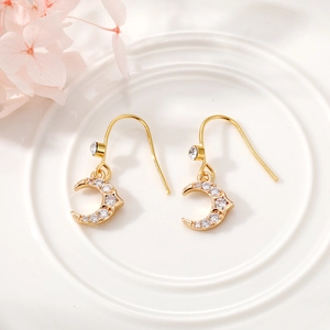 Detailed macro view of gold crescent moon earrings featuring shimmering clear rhinestones