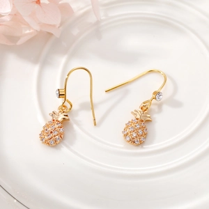 Close-up of gold pineapple drop earrings featuring sparkling crystal pavé details