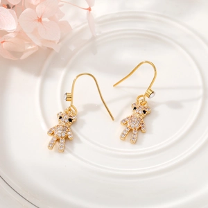 Detail of gold bear earrings with pavé white crystals on a ceramic display tray