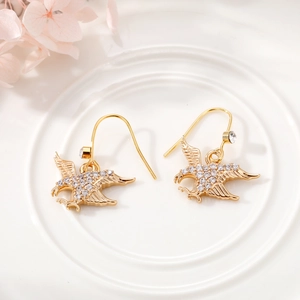 Detailed macro view of golden eagle drop earrings with sparkling white crystals