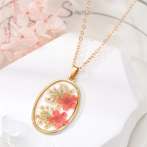 Oval gold pendant necklace with real dried pink flowers in clear resin on stone base