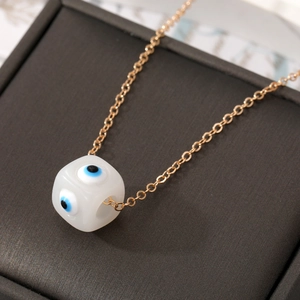 Detailaufnahme des würfelförmigen Evil Eye Anhängers an einer goldenen Halskette