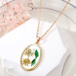 Detailed macro of oval resin pendant with real yellow dried flowers on gold chain