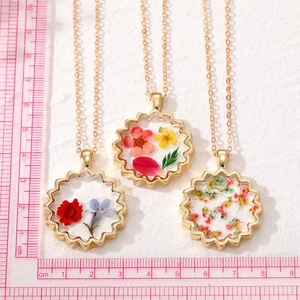 Collier bohème avec fleurs séchées en résine transparente et bordure dorée ondulée