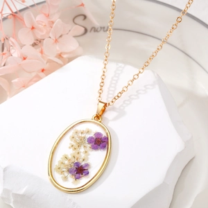 Detailed macro view of the oval resin pendant featuring purple and white dried flowers