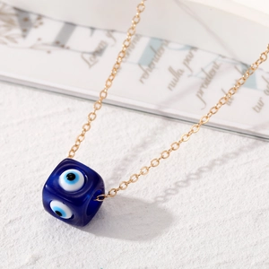 Detailansicht eines blauen Harzwürfel-Anhängers mit bösem Blick an einer feinen Goldkette