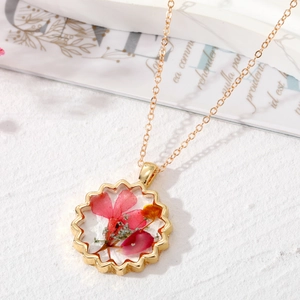Détail du collier bohème doré avec de vraies fleurs séchées rouges et roses dans la résine