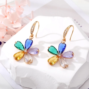 Primer plano de pendientes de flores de cristal de colores con ganchos dorados en piedra