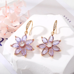 Detalle macro de pendientes chapados en oro con pétalos de cristal púrpura e incrustaciones