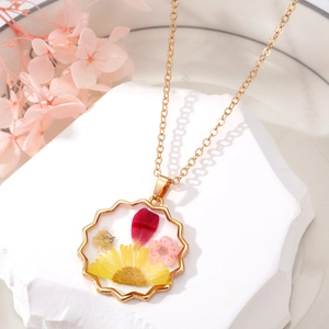 Gros plan du pendentif bohème avec fleurs séchées rouges et jaunes et cadre doré