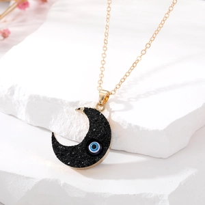 Boho-Halskette mit schwarzem Mondanhänger und blauem Auge auf weißem Stein präsentiert