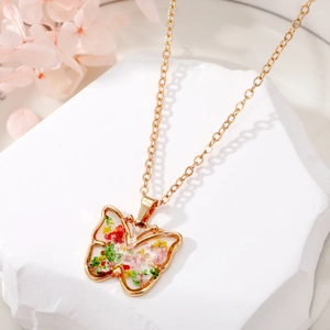 Gros plan du collier papillon avec de vraies fleurs séchées et un cadre en résine dorée