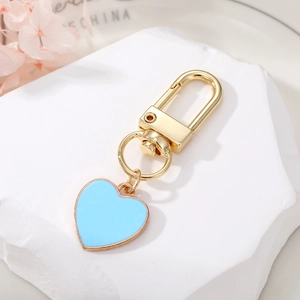 Sky blue heart keychain with 18k gold lobster clasp on white stone display