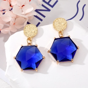 Detailopname van zeshoekige blauwe kristallen oorbellen met gehamerde gouden studs