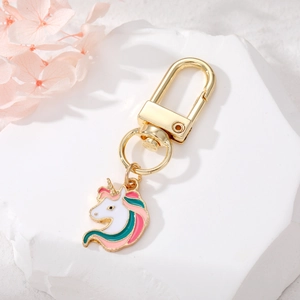 Cute cartoon unicorn keychain with rainbow mane in gold finish on elegant white stone base
