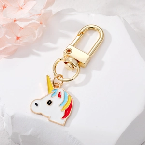Detailed view of unicorn keychain with gold clasp and colorful enamel on a stone pedestal
