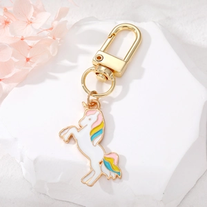 Detail of cute unicorn keychain with rainbow colors on white stone and pink flowers