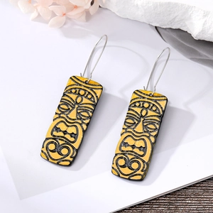 Detailed close-up of yellow African Tiki face earrings with black tribal patterns
