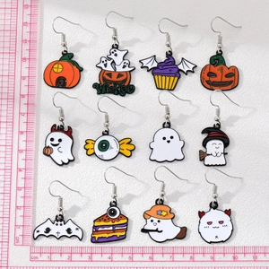 Macro shot of 12-pair Halloween enamel earring set with ruler measuring size on white sand
