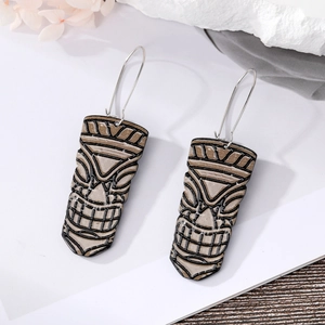 Ethnic Tiki mask dangle earrings with Polynesian totem design on white rock background