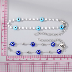 Detail of blue evil eye bracelets with beads and metal pendant on a measurement grid