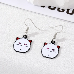 Detail of cute devil earrings with white enamel charms and red horns on Vogue magazine