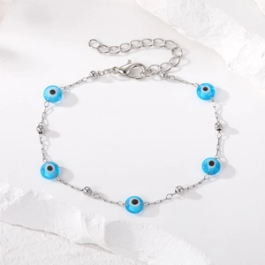 Silver evil eye pearl bracelet for women featuring light blue beads on a white stone background