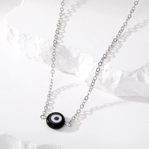 Minimalistische boze oog ketting met zilveren ketting op witte steen, scherpe schaduw