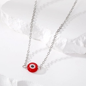 Macro-opname van rode hars boze oog hanger aan een zilveren ketting op witte stenen