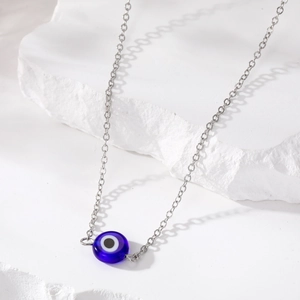 Macro-opname van zilveren ketting met donkerblauwe hars boze oog hanger op witte steen