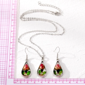 Detailed close-up of water drop shaped resin pendants with real dried red rose buds