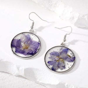 Macro detail of handmade clear resin drop earrings with natural purple dried flowers