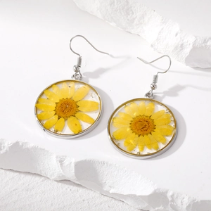 Handmade resin drop earrings with real yellow daisy flowers on a white stone base
