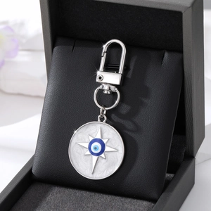 Nahaufnahme des silbernen Evil Eye Schlüsselanhängers mit blauem Emaille auf Lederbox